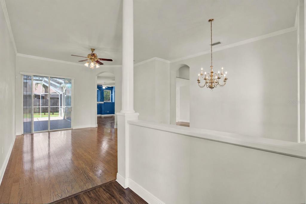 An interior view shows a living area with hardwood floors, a ceiling fan, and chandelier — 3165 PRIDES CROSSING, TARPON SPRINGS, FL