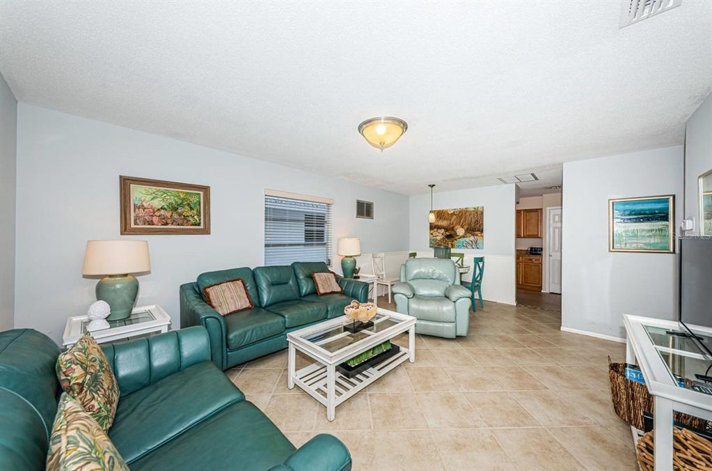 A living room features teal leather sofas, a white coffee table, and light tile flooring — 6020 MIDNIGHT PASS ROAD UNIT 40, SARASOTA, FL