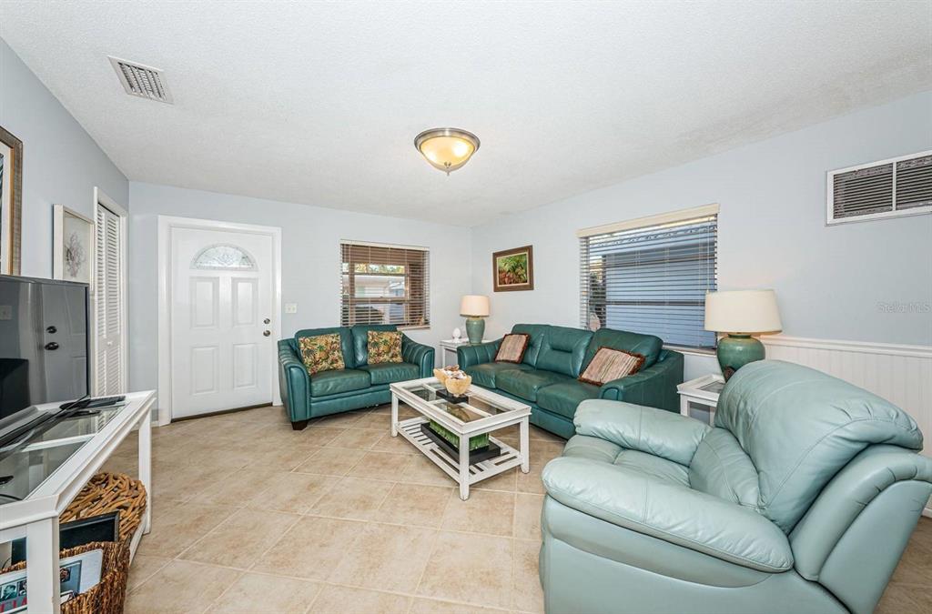 A living room features light blue walls, tile flooring, and a set of teal leather furniture — 6020 MIDNIGHT PASS ROAD UNIT 40, SARASOTA, FL