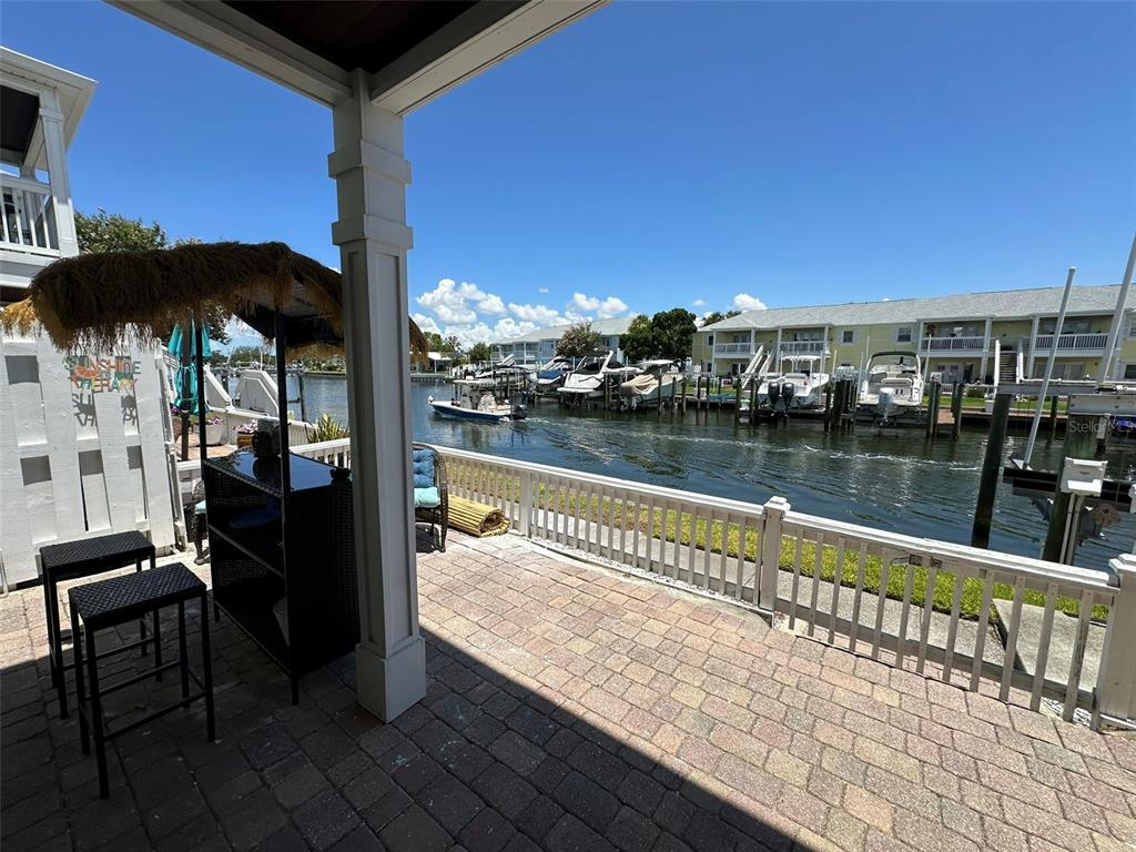 A paved patio overlooks a canal with docked boats and multi-story residential buildings — 5006 STARFISH DR SE UNIT A, ST PETERSBURG, FL