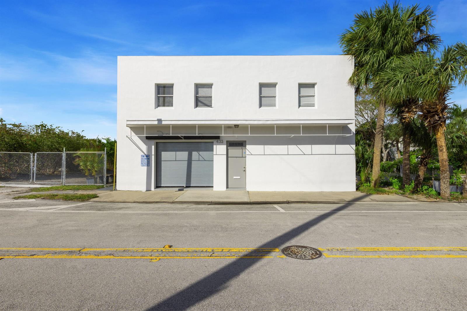 A two-story white commercial building features a roll-up garage door, a pedestrian door, and palm trees — 433 Flamingo Drive, West Palm Beach FL 33401, WEST PALM BEACH, FL