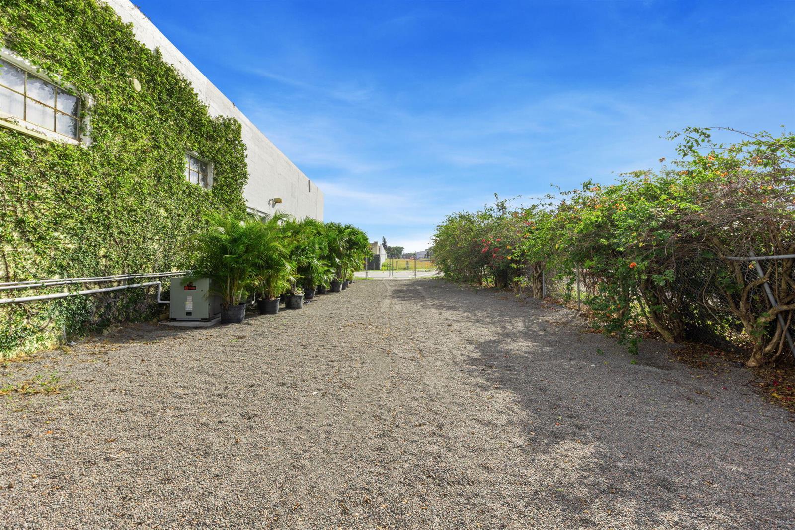 A gravel path runs between a vine-covered building wall and a flowering hedge — 433 Flamingo Drive, West Palm Beach FL 33401, WEST PALM BEACH, FL