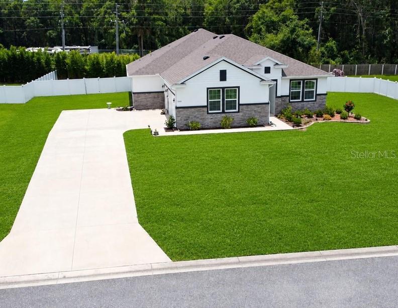 An aerial view shows a single-story house with a white exterior, stone accents, and driveway — 1340 SE 63RD COURT ROAD, OCALA, FL