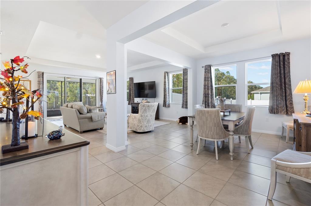 An open-concept living and dining area features tile flooring, neutral walls, and large windows — 1340 SE 63RD COURT ROAD, OCALA, FL