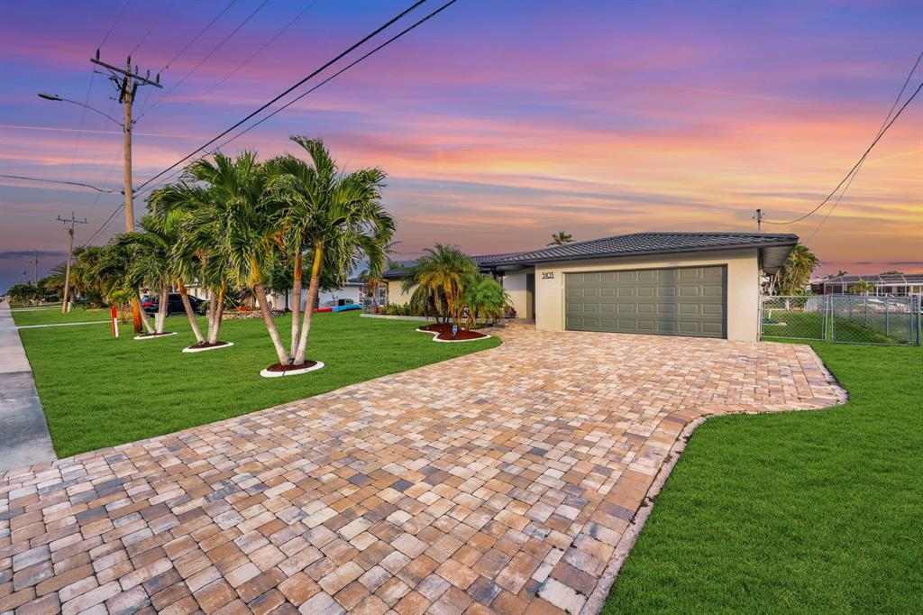 A single-story house with a paved driveway, palm trees, and a green garage door — 5103 PELICAN BOULEVARD, CAPE CORAL, FL