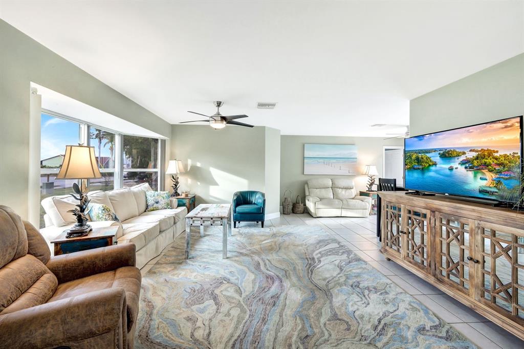 A living room features a large area rug, a white sofa, and a television console — 5103 PELICAN BOULEVARD, CAPE CORAL, FL