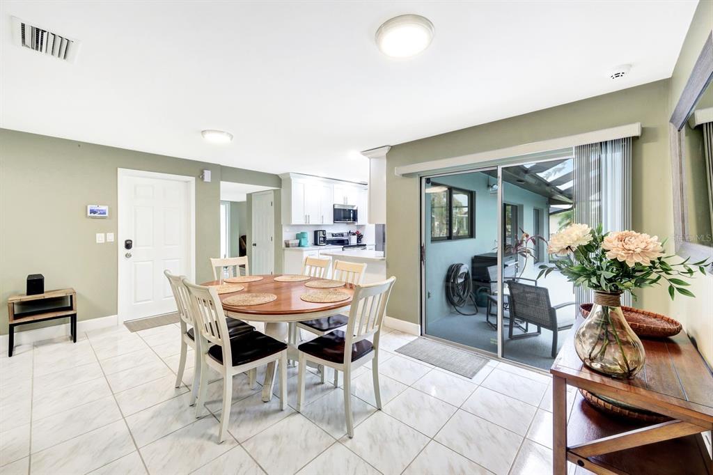 A dining area with a round table, tile floors, and a sliding glass door to a patio — 5103 PELICAN BOULEVARD, CAPE CORAL, FL