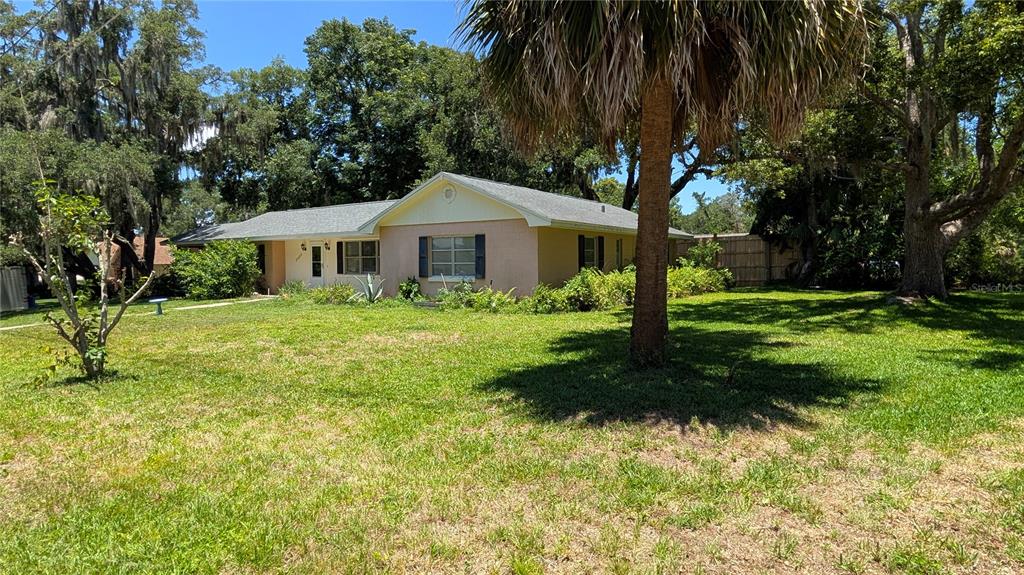 A single-story house with a light-colored exterior sits on a grassy lot with trees — 2469 BROADVUE AVENUE, EUSTIS, FL