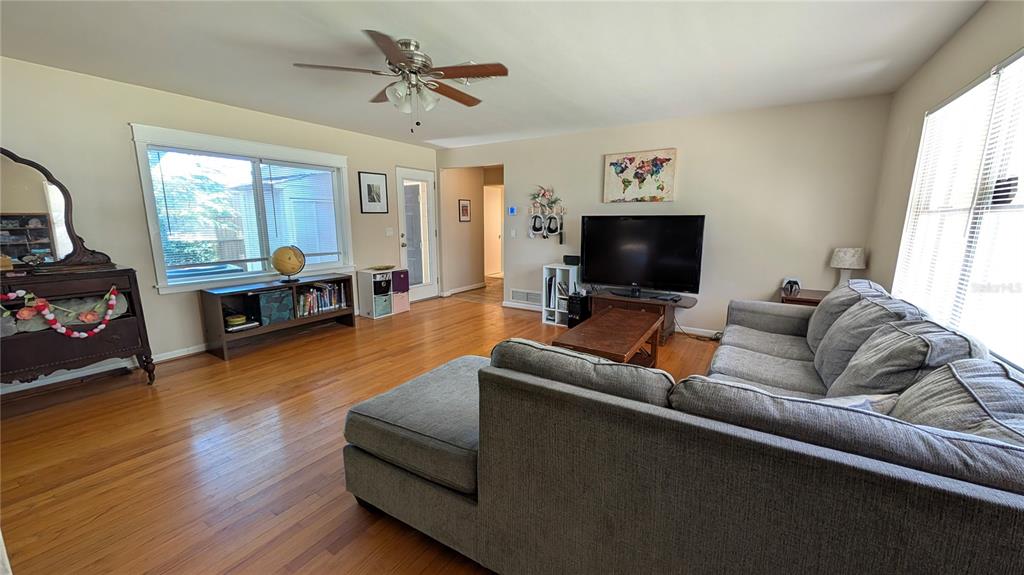 A living room features hardwood floors, a gray sectional sofa, and a television console — 2469 BROADVUE AVENUE, EUSTIS, FL