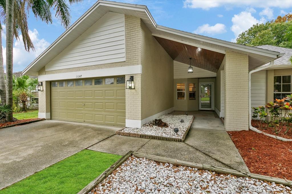 The exterior of a single-story house features a brick facade, a garage, and a covered entryway — 11647 FOX CREEK DRIVE, TAMPA, FL