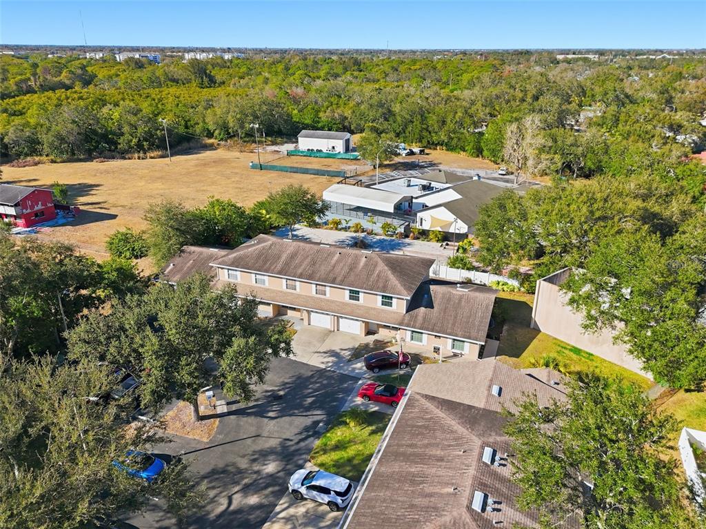 An aerial view shows a multi-unit residential building with a parking lot and surrounding trees — 7363 62ND AVENUE N, PINELLAS PARK, FL