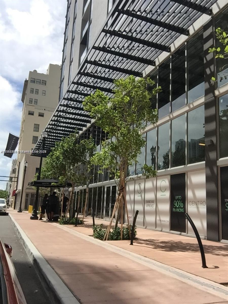 A modern building exterior features a metal trellis, glass storefronts, and sidewalk landscaping — 151 SE 1st St # 1505, Miami FL 33131, MIAMI, FL