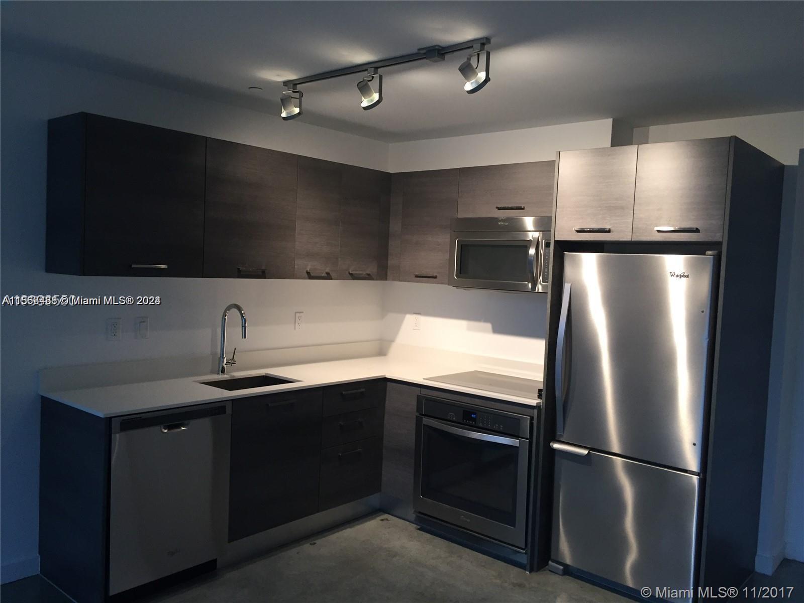 A modern kitchen features dark wood cabinetry, stainless steel appliances, and white countertops — 151 SE 1st St # 1505, Miami FL 33131, MIAMI, FL