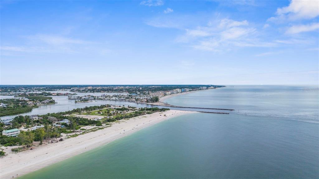 An aerial view shows a sandy beach, a jetty, and a waterway leading to the ocean — 216 PAVONIA ROAD, NOKOMIS, FL
