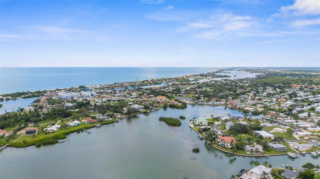 An aerial view shows a coastal residential neighborhood situated along a bay and oceanfront — 216 PAVONIA ROAD, NOKOMIS, FL