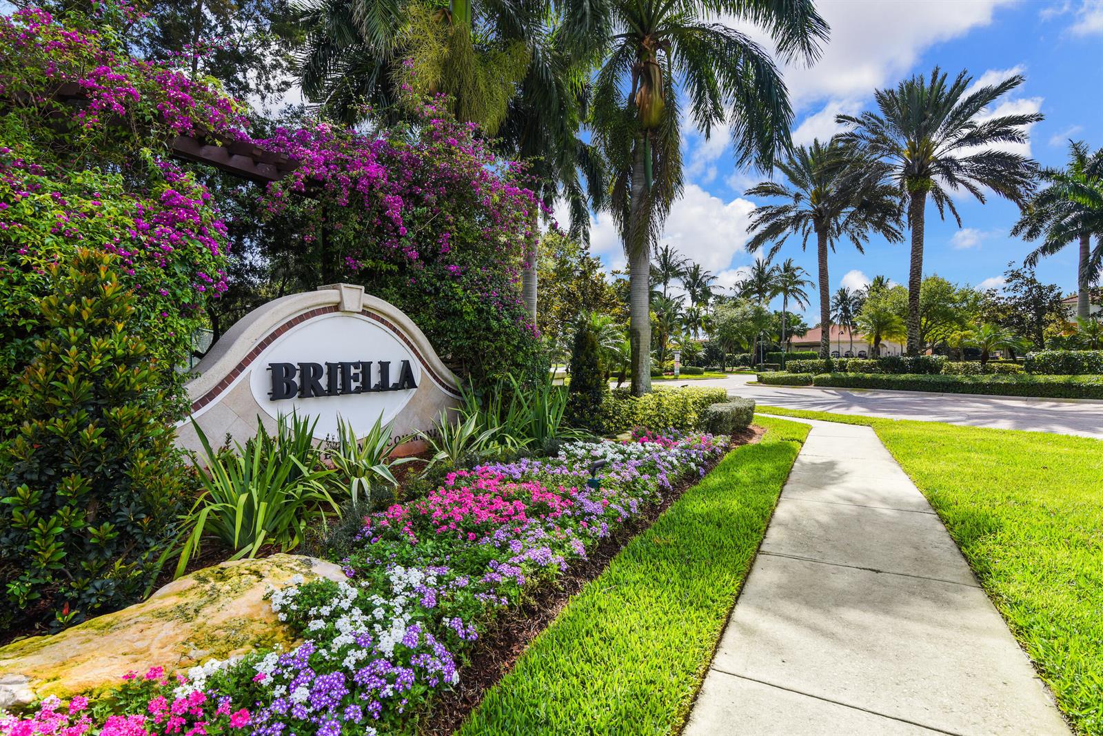 A stone sign for the Briella community stands beside a sidewalk and tropical landscaping — 7392 Briella Drive, Boynton Beach FL 33437, BOYNTON BEACH, FL