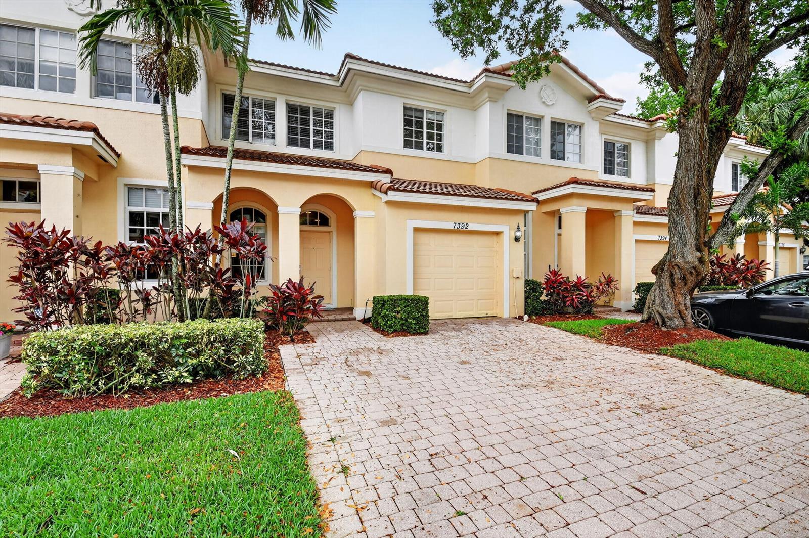 A two-story townhouse with a beige stucco facade, tiled roof, and a paved driveway — 7392 Briella Drive, Boynton Beach FL 33437, BOYNTON BEACH, FL