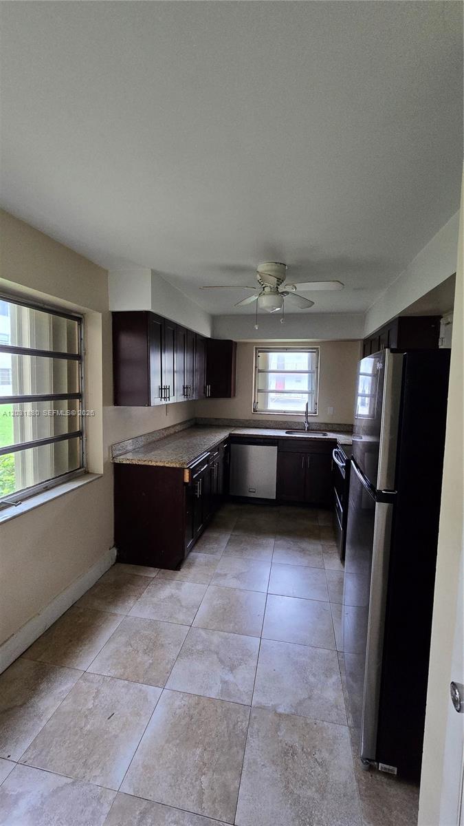 A kitchen features dark wood cabinets, granite countertops, stainless steel appliances, and tiled flooring — 1450 NE 191st St # 106, Miami FL 33179, MIAMI, FL