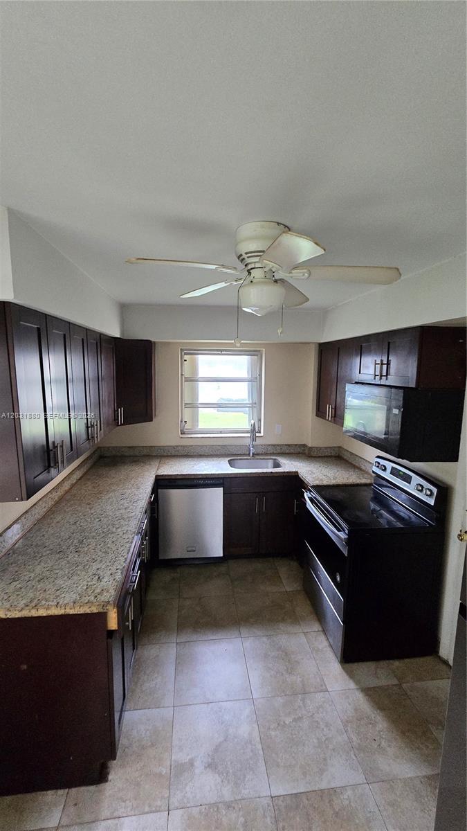 A kitchen features dark wood cabinets, granite countertops, stainless steel appliances, and a ceiling fan — 1450 NE 191st St # 106, Miami FL 33179, MIAMI, FL