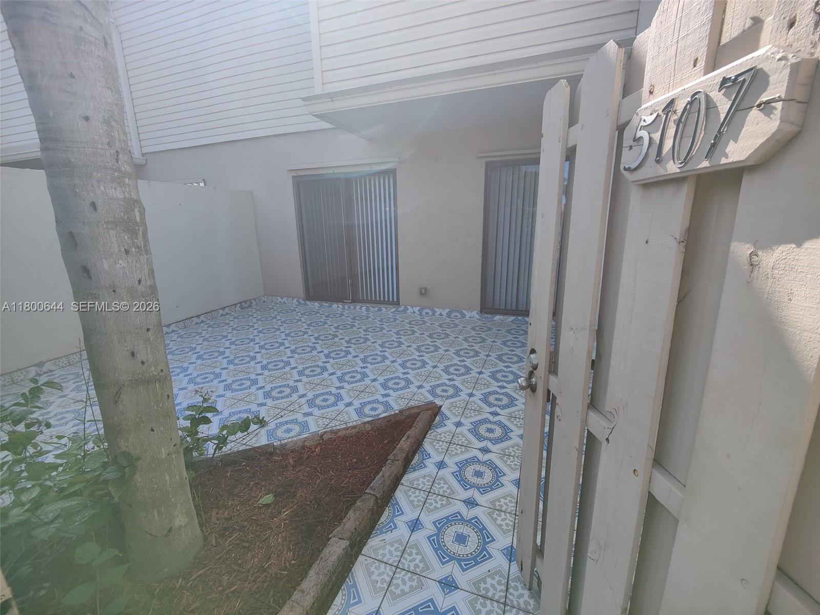 A patio with patterned tile flooring is enclosed by a white fence and building walls — 616 Executive Center Dr # 107, West Palm Beach FL 33401, WEST PALM BEACH, FL