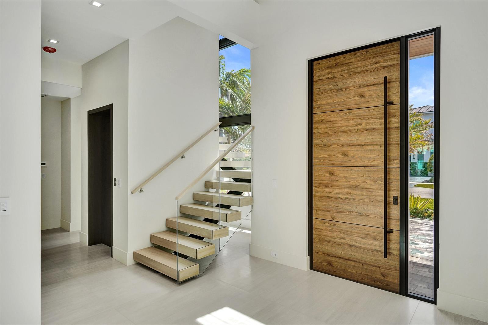 An entryway features a wood-paneled front door, a floating staircase, and light-colored tile flooring — 365 NE 3rd Street, Boca Raton FL 33432, BOCA RATON, FL