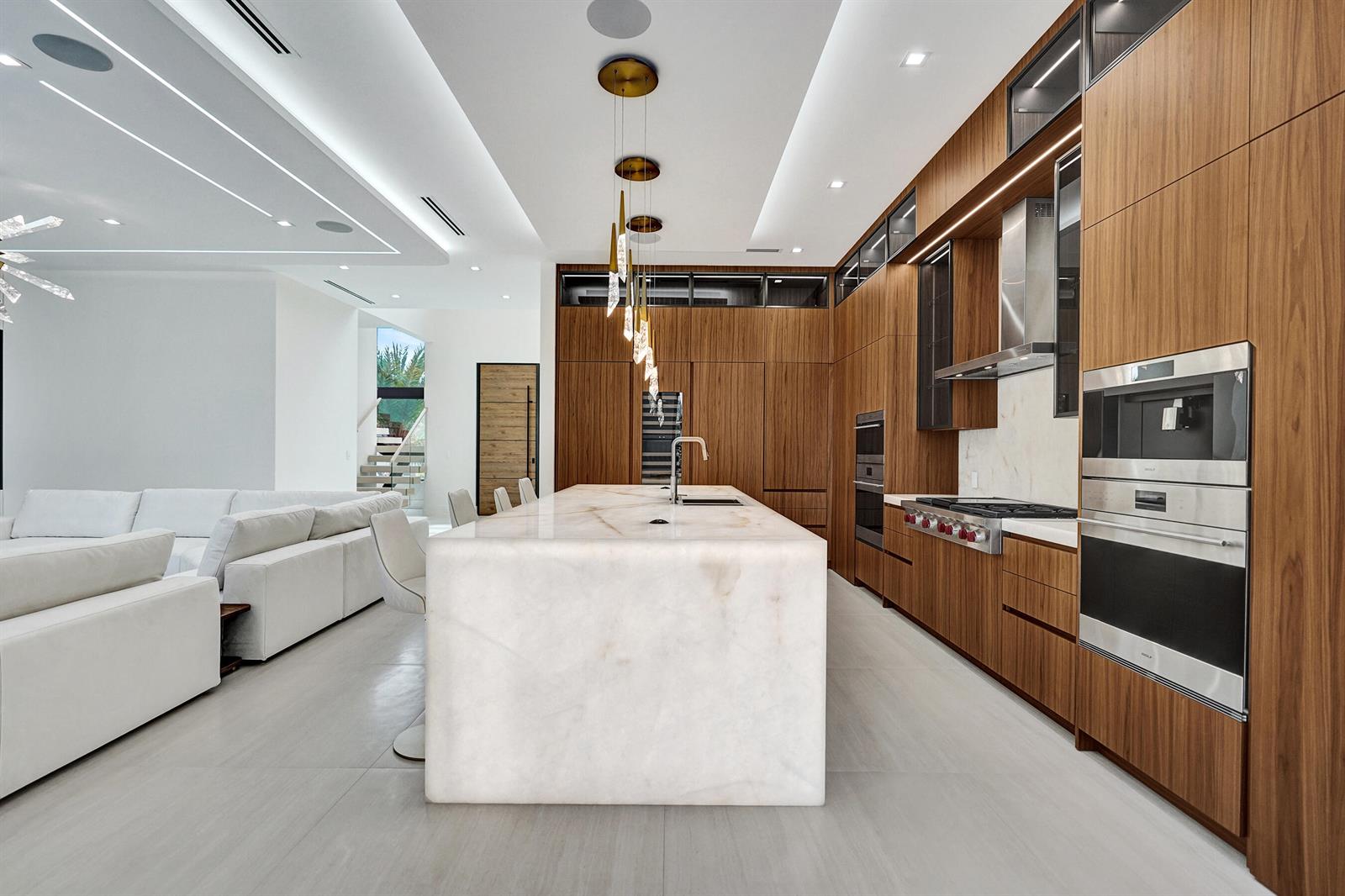 A modern kitchen features wood cabinetry, a large white stone island, and integrated stainless appliances — 365 NE 3rd Street, Boca Raton FL 33432, BOCA RATON, FL