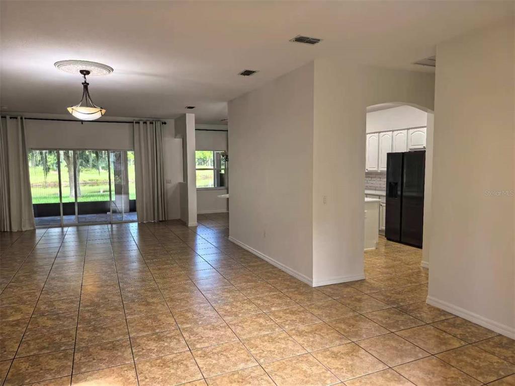 A tiled living area leads to a kitchen with black appliances and a rear patio — 3520 SHOREWOOD DRIVE, KISSIMMEE, FL