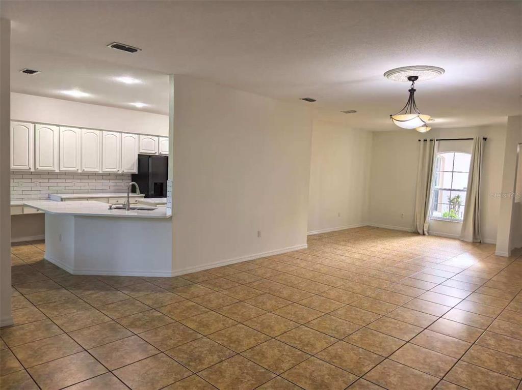 A kitchen with white cabinets and a breakfast bar opens to a tiled dining area — 3520 SHOREWOOD DRIVE, KISSIMMEE, FL