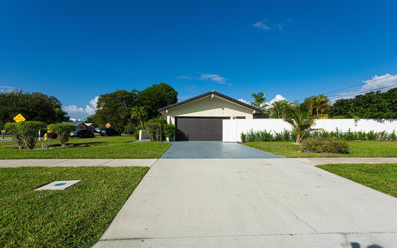 A single-story house with a dark garage door and a white fence in a suburban neighborhood — 2013 Ardley Road, North Palm Beach FL 33408, NORTH PALM BEACH, FL