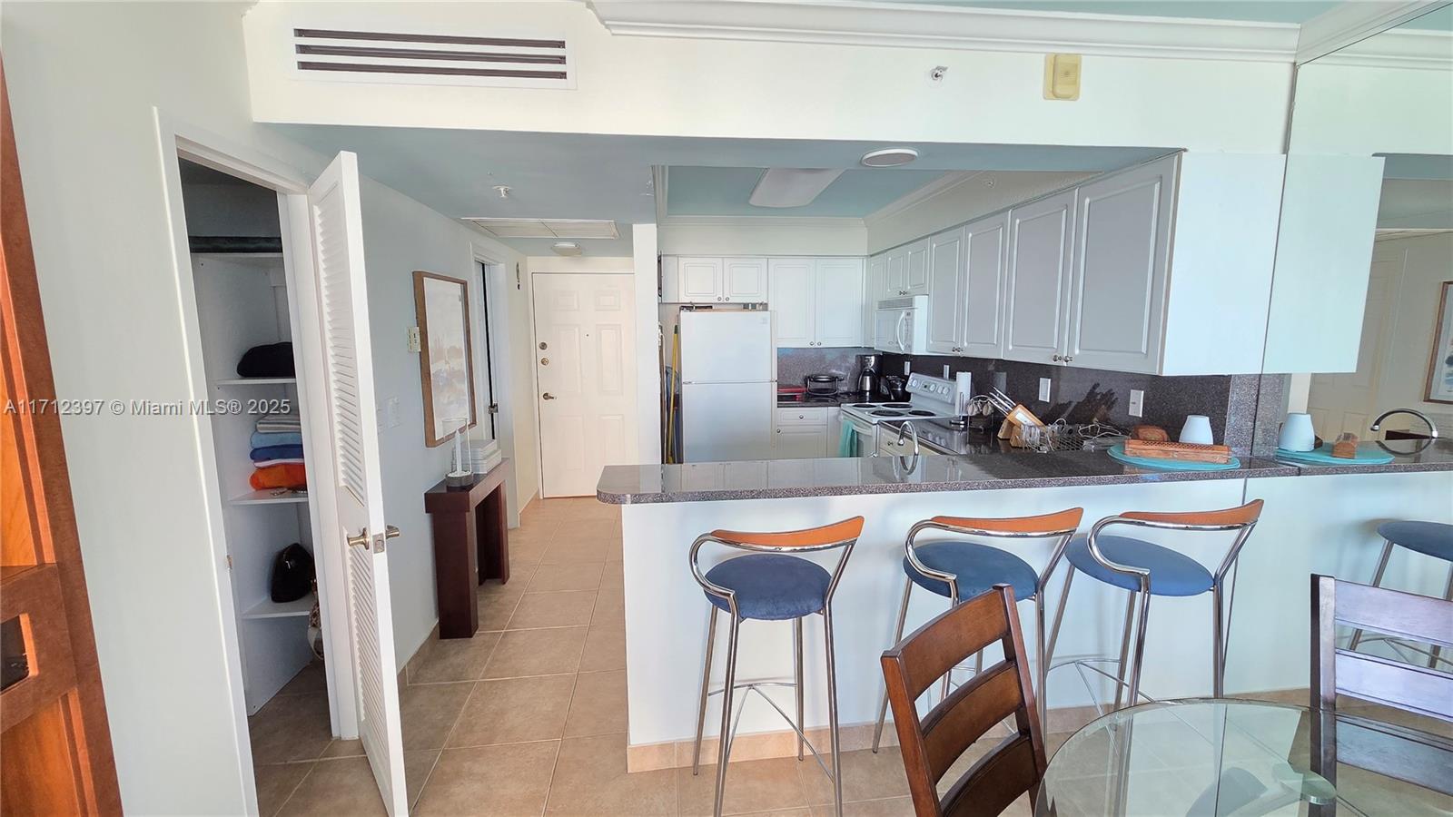 A kitchen with white cabinets and a breakfast bar with three stools — 2501 S OCEAN DRIVE # 809, Hollywood FL 33019, HOLLYWOOD, FL