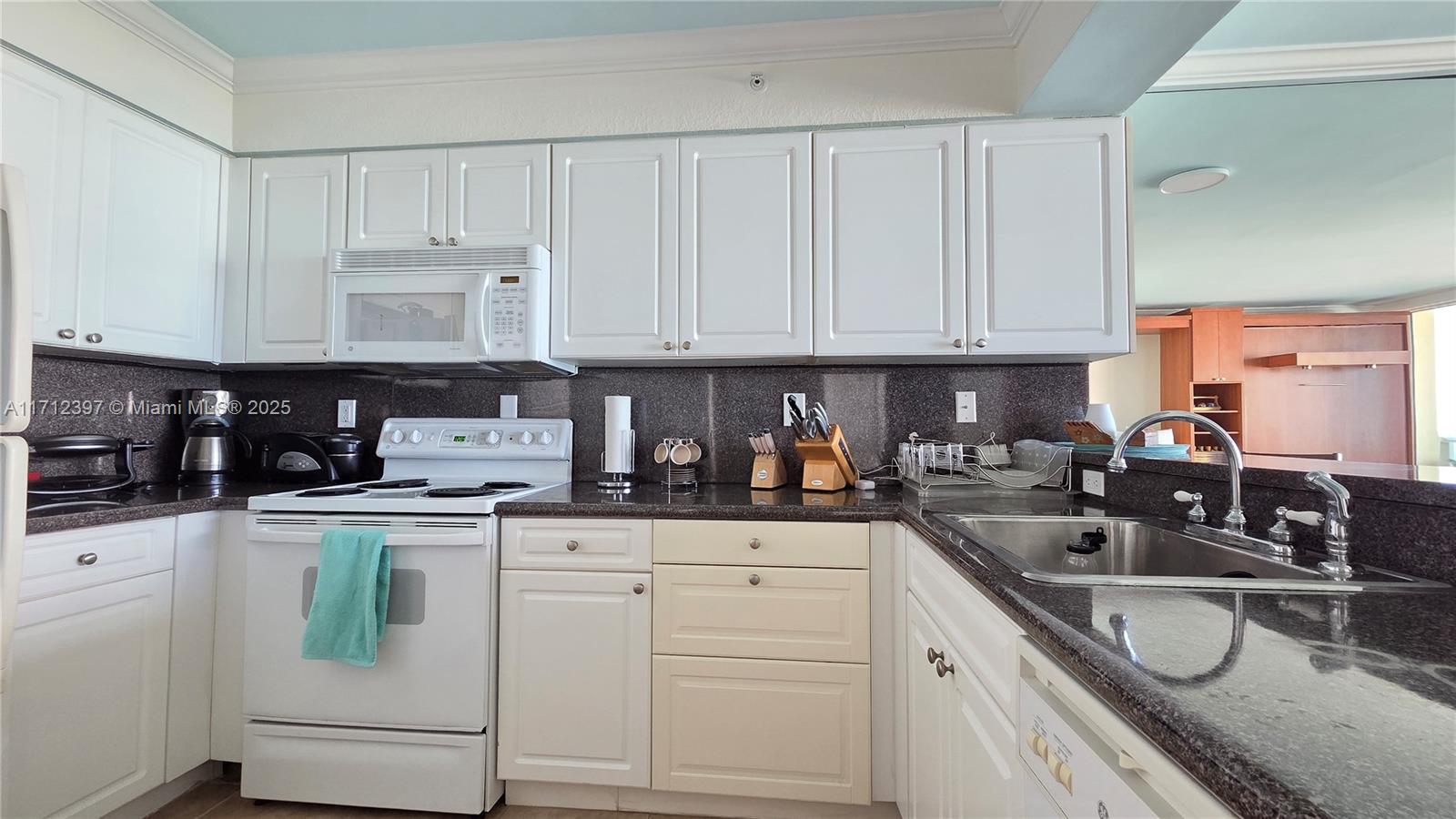 A kitchen features white cabinetry, dark granite countertops, and white appliances — 2501 S OCEAN DRIVE # 809, Hollywood FL 33019, HOLLYWOOD, FL