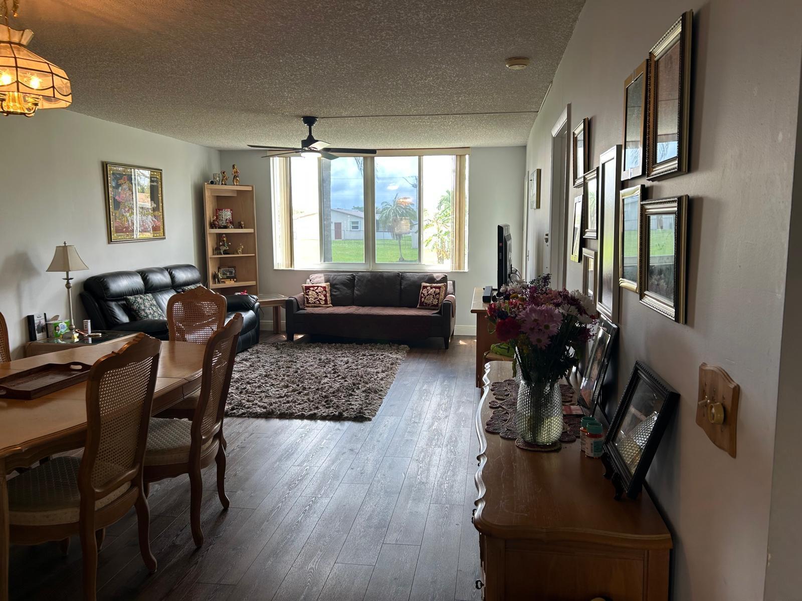 A living and dining area features wood-look flooring, a ceiling fan, and a large window — 6670 Royal Palm Boulevard # 112k, Margate FL 33063, MARGATE, FL
