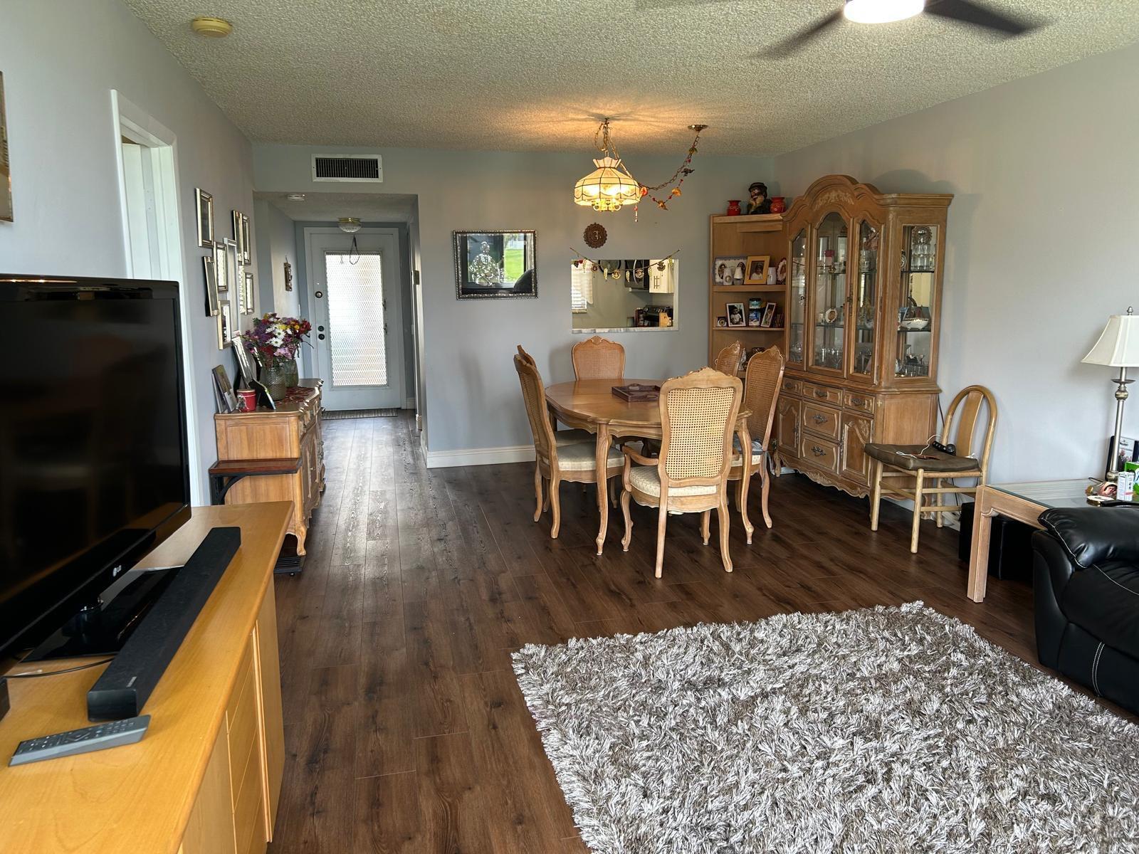 A dining area with a wooden table and hutch sits adjacent to a living space — 6670 Royal Palm Boulevard # 112k, Margate FL 33063, MARGATE, FL