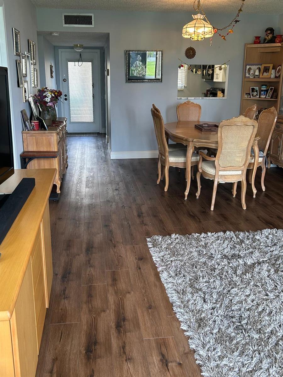 A dining area and entryway feature wood-look flooring, light gray walls, and a wooden table — 6670 Royal Palm Boulevard # 112k, Margate FL 33063, MARGATE, FL