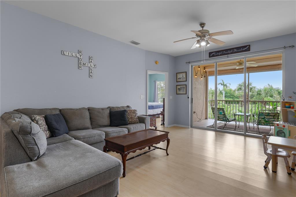 A living room features a gray sectional sofa, a wooden coffee table, and sliding glass doors — 14201 PATTY BERG DRIVE UNIT 201, FORT MYERS, FL