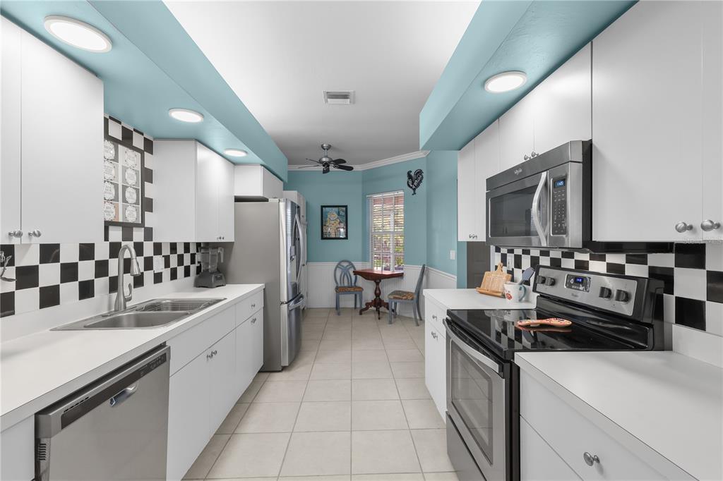 A kitchen with white cabinets, black and white checkered backsplash, and light blue ceiling accents — 14201 PATTY BERG DRIVE UNIT 201, FORT MYERS, FL