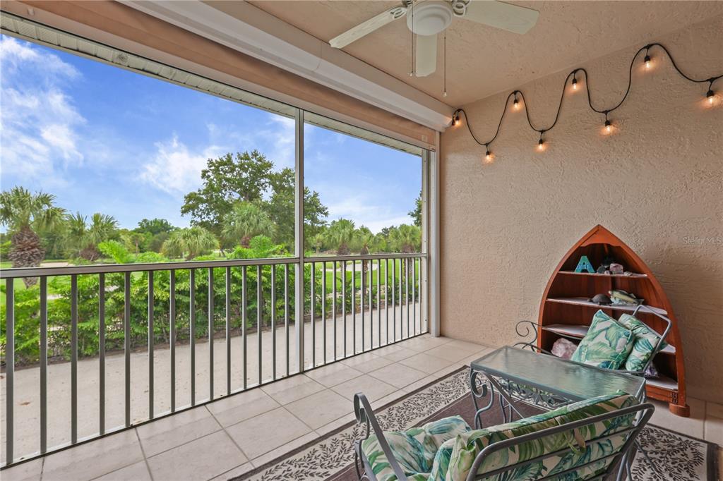 A screened-in patio features tile flooring, a ceiling fan, string lights, and a boat-shaped shelf — 14201 PATTY BERG DRIVE UNIT 201, FORT MYERS, FL