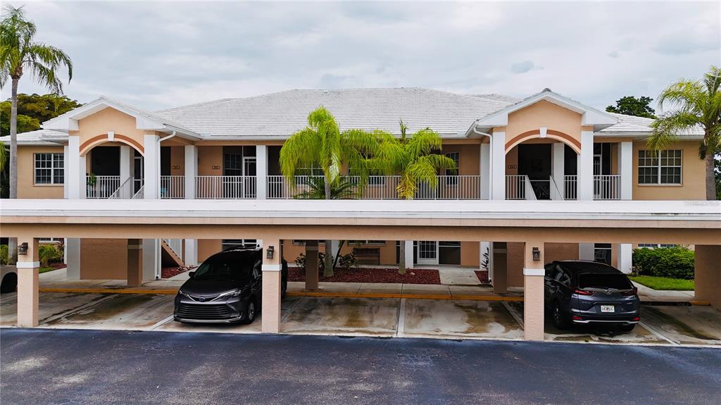 A two-story apartment building features a covered parking area with two parked vehicles — 14201 PATTY BERG DRIVE UNIT 201, FORT MYERS, FL