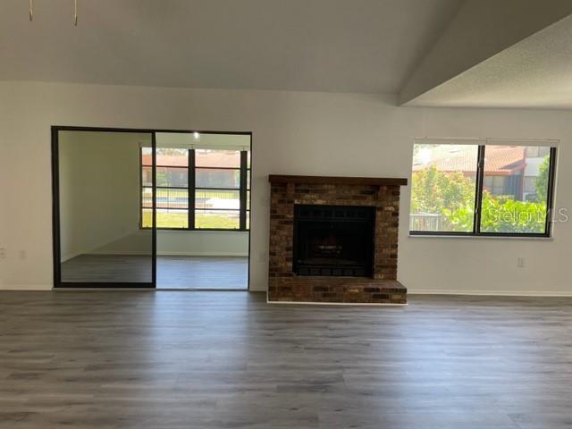 A living room features light wood-look flooring, a brick fireplace, and a sliding glass door — 747 SORRENTO INLET, NOKOMIS, FL