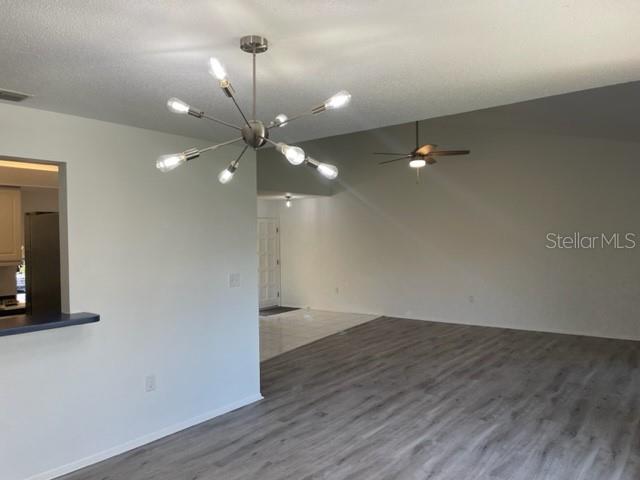 An open living area features light wood-look flooring, a modern chandelier, and a ceiling fan — 747 SORRENTO INLET, NOKOMIS, FL