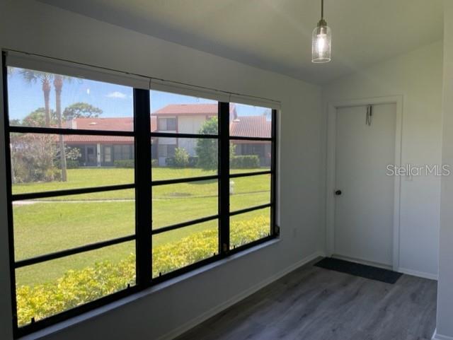 A sunroom with large windows, light wood-look flooring, and a single door — 747 SORRENTO INLET, NOKOMIS, FL