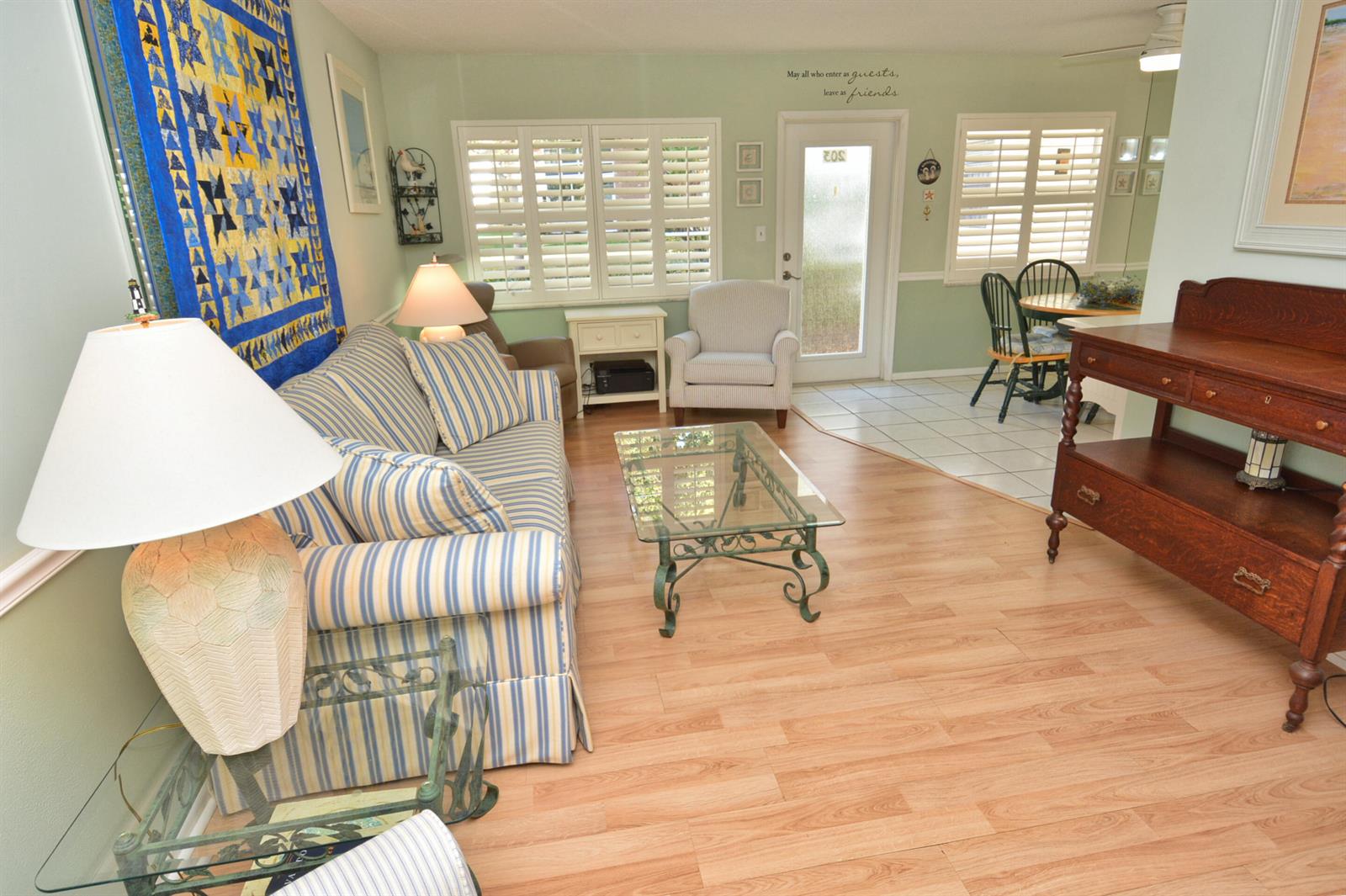 A living room with striped furniture, a glass coffee table, and light wood flooring — 1225 NW 21st Street # 203, Stuart FL 34994, STUART, FL