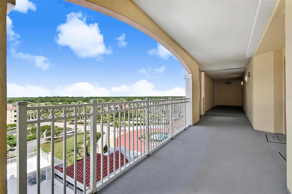A covered outdoor balcony with a white metal railing overlooks a parking lot and trees — 200 OCEAN CREST DRIVE UNIT 622, PALM COAST, FL