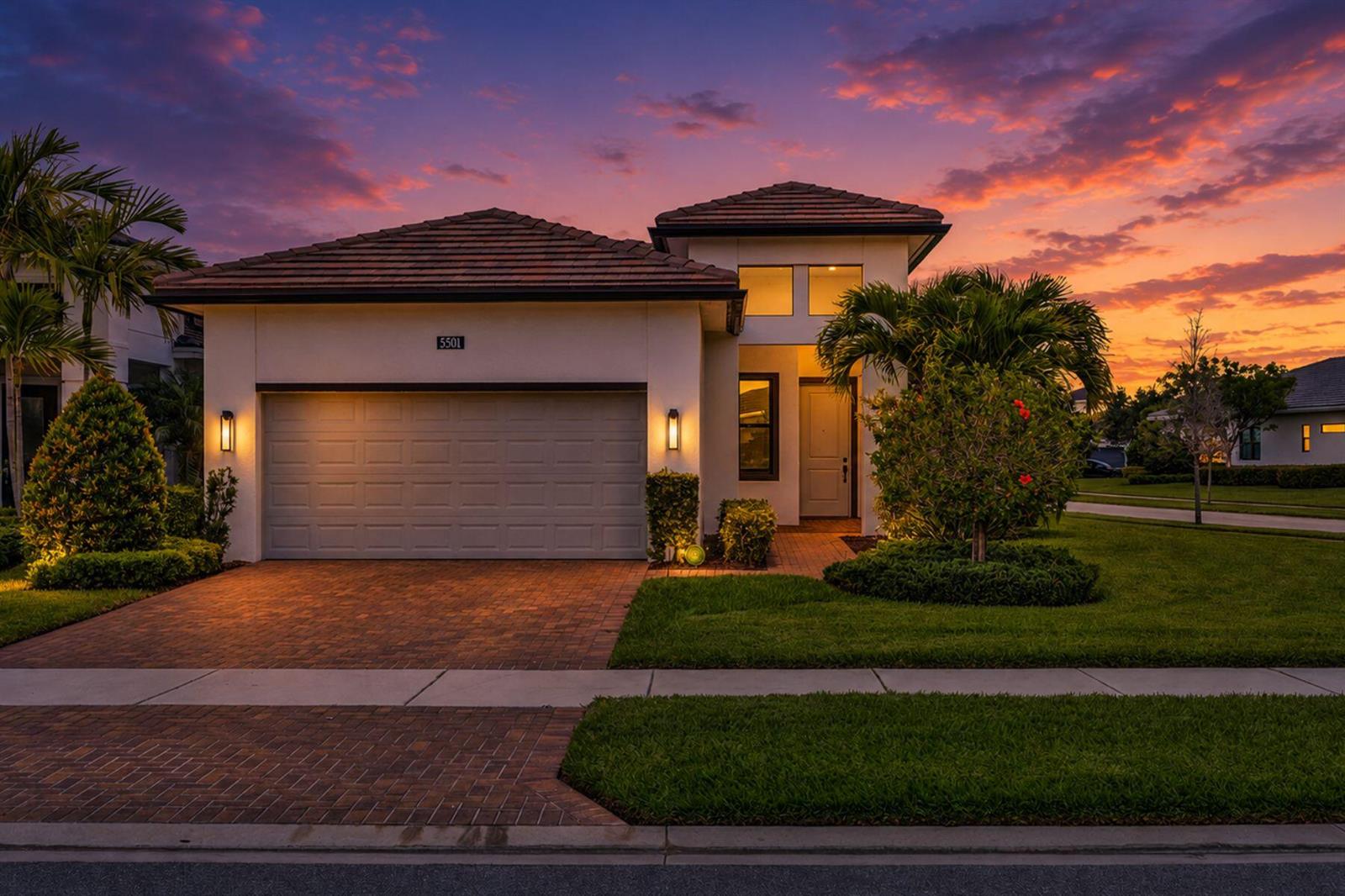 A single-story house with a two-car garage and a paved driveway at sunset — 5501 Santa Rosa Lane, Westlake FL 33470, WESTLAKE, FL