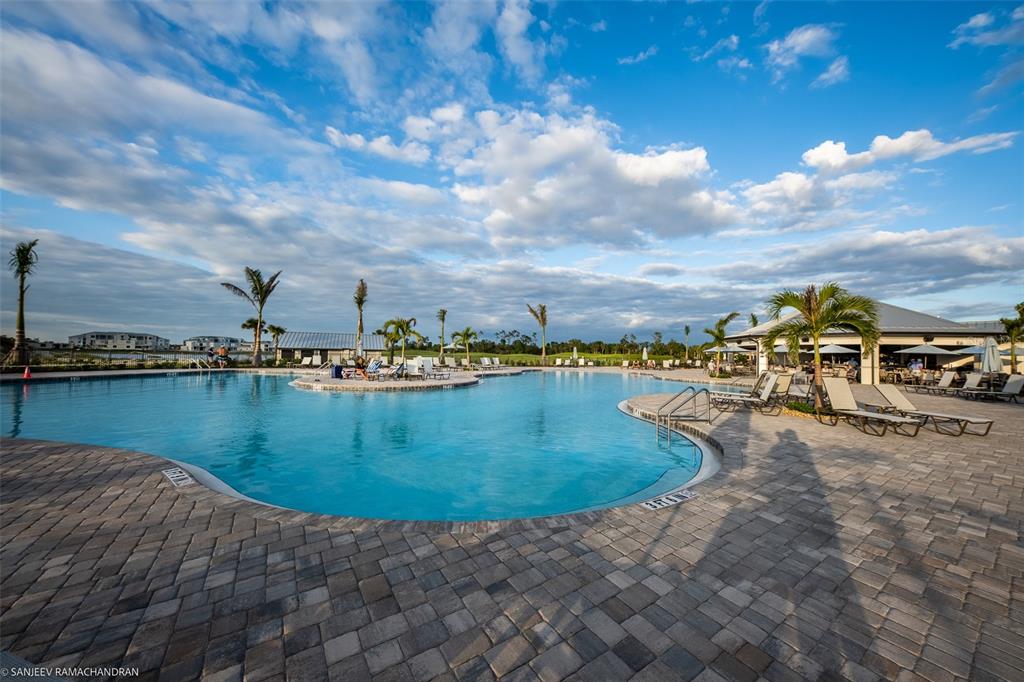 A large outdoor swimming pool with lounge chairs and palm trees under a cloudy sky — 14051 HERITAGE LANDING BOULEVARD UNIT 511, PUNTA GORDA, FL