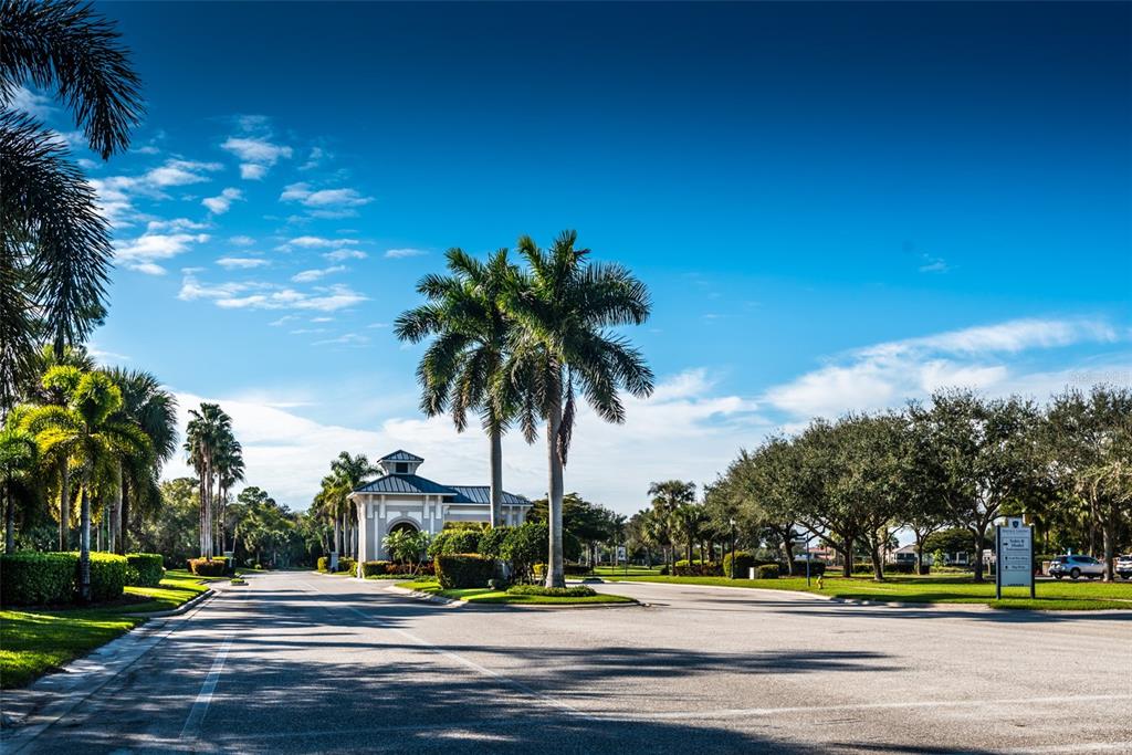 A paved road leads toward a gated community entrance with palm trees and a guardhouse — 14051 HERITAGE LANDING BOULEVARD UNIT 511, PUNTA GORDA, FL