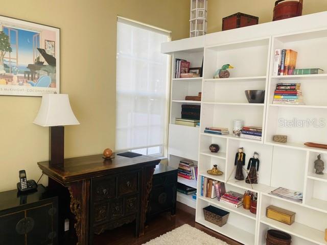 A home office features a dark wood desk, a white bookshelf, and a framed wall print — 7711 WHITEBRIDGE GLEN, UNIVERSITY PARK, FL