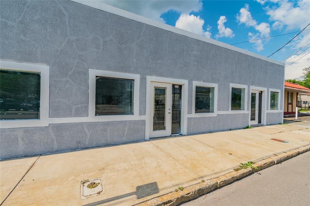 A gray stucco commercial building features multiple large windows and a glass-paned front door — 3410 E 7TH AVENUE, TAMPA, FL