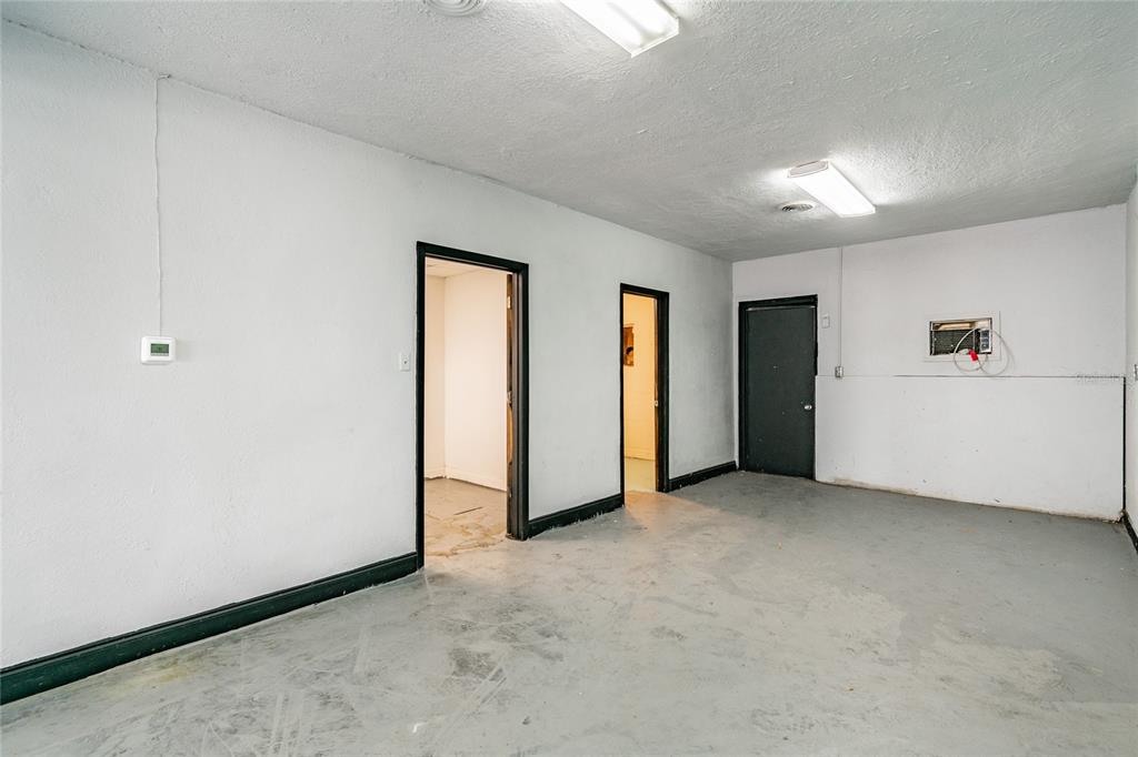An interior room with white walls, a gray concrete floor, and three doorways — 3410 E 7TH AVENUE, TAMPA, FL