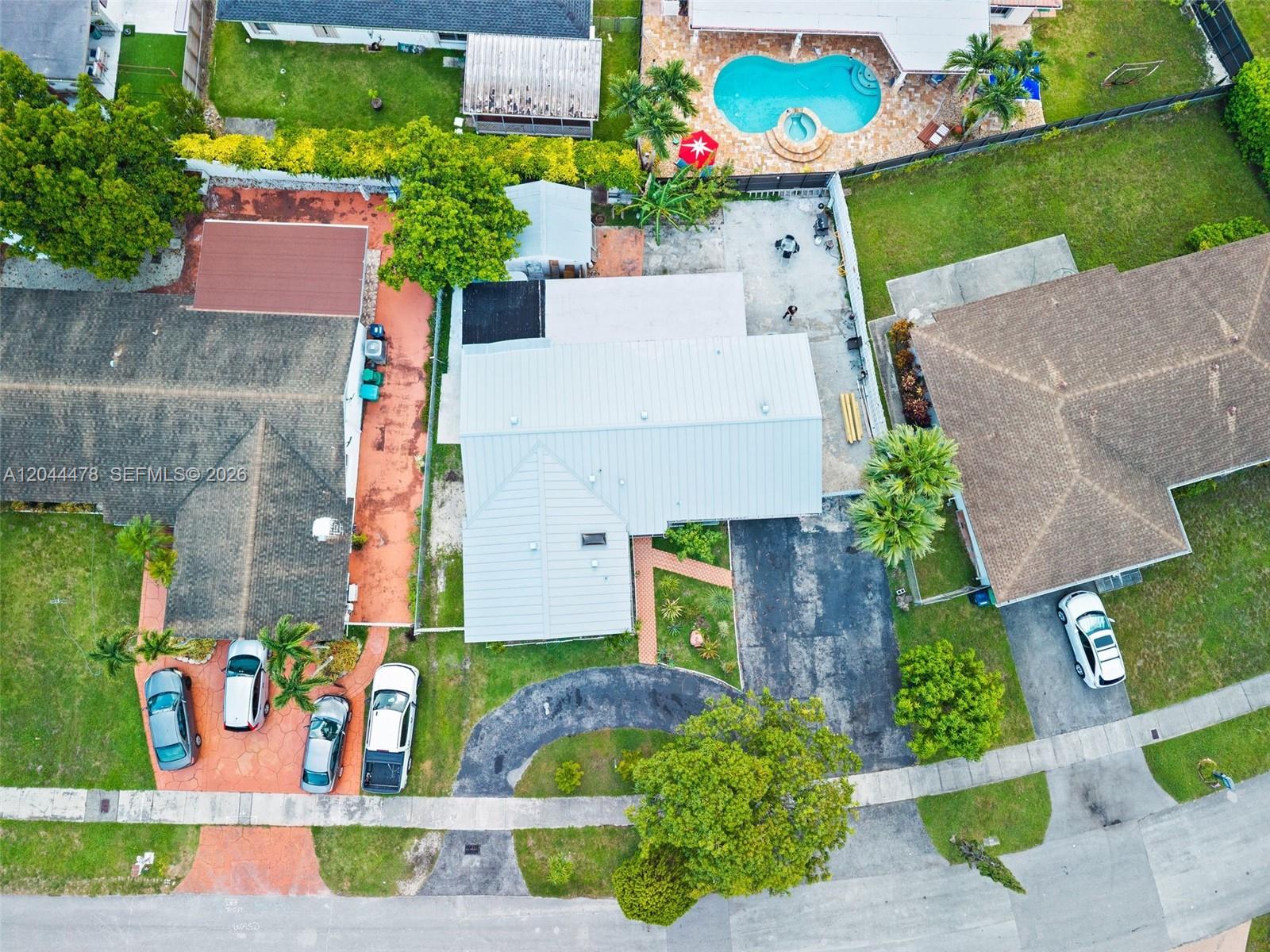 An aerial view shows three residential houses with driveways, lawns, and a backyard swimming pool — 8014 SW 133rd Ct, Miami FL 33183, MIAMI, FL